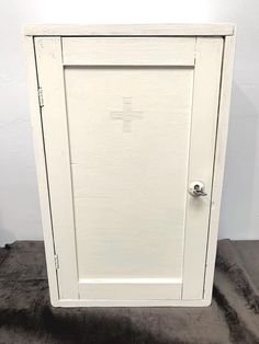 a white cabinet sitting on top of a carpeted floor in front of a wall