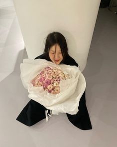 a woman sitting on the ground holding a bouquet of flowers