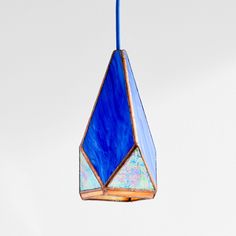 a blue and white glass hanging from a hook on a ceiling fixture with a cord attached to it