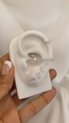 a woman's hand holding an ear with three diamonds on it