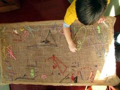 a young boy is playing with an art project on a piece of burlock