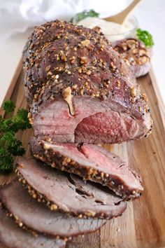 sliced roast beef on a cutting board with parsley sprinkled in sesame seeds