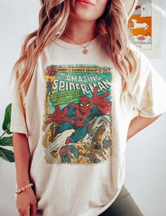 a woman wearing a white spiderman t - shirt with her hands on her hips