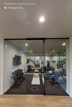 an empty gym room with glass walls and mirrors on the wall, as well as exercise equipment