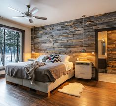 a bedroom with wood paneling and a bed in the middle, next to a large window