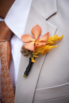 a boutonniere with an orange flower is worn on a man's white suit