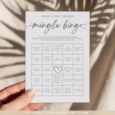 a hand holding up a baby shower game card with the words jungle bingo written on it