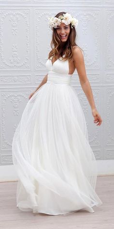 a woman wearing a white dress and flower in her hair, standing on the floor