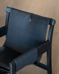 a black leather chair sitting on top of a wooden floor