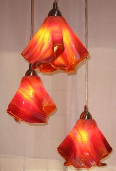 three red and yellow glass lights hanging from a ceiling