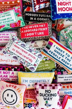 many colorful pillows with different sayings on them