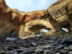 an image of a rocky beach with rocks in the foreground and large rock formations on either side