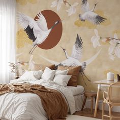 there is a bed with two birds painted on the wall and one bird flying in the air