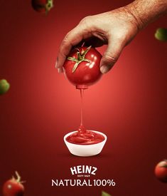 a tomato being drizzled with ketchup by a hand on a red background