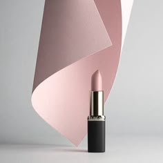 a pink lipstick sitting on top of a white table next to an abstract wallpaper