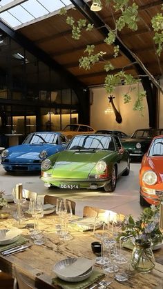 a group of cars are parked in a garage next to tables and chairs with place settings on them