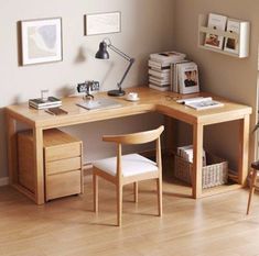 a wooden desk sitting in front of a window next to a chair and table with a lamp on it