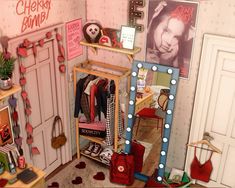 a doll house with clothes and accessories on the floor, including a dressing room mirror