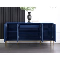 a blue sideboard with two open shelves and a vase on the top, in front of a black wall