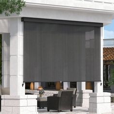 an outdoor covered patio area with chairs and table in front of the building that has a large awning over it