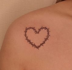 a heart shaped tattoo on the back of a woman's shoulder