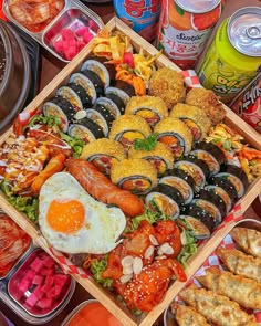 an assortment of food items displayed in wooden trays on table with cans of soda