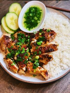 a plate with chicken, rice and cucumbers on it