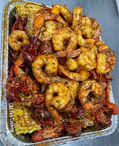 shrimp and corn on the cob with seasoning in a tin container, ready to be eaten