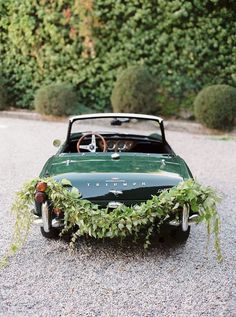 an old car with plants growing out of it's roof is parked on gravel