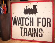 a sign that says watch for trains next to a vase with pens and pencils