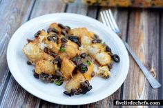 a white plate topped with black beans and tater tots next to a fork