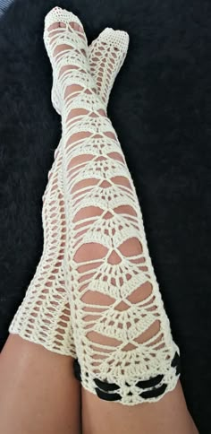 a woman's legs with white crocheted stockings on top of black carpet