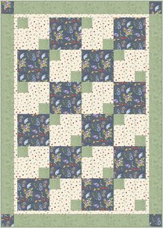 a blue and white quilt with flowers on the front, green border around the edges