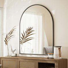 a mirror sitting on top of a wooden cabinet in a living room next to a window