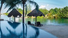 an empty pool with chairs and umbrellas next to the water