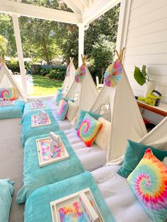 a group of teepee tents sitting on top of a bed covered in blue and pink pillows