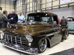 people are looking at an antique car on display