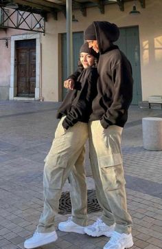 two people standing next to each other in front of a building with an awning