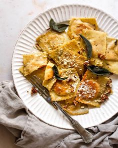 a white plate topped with ravioli and sage