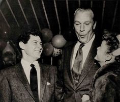 black and white photograph of two men in suits talking to each other at a party