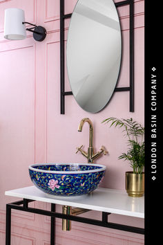 a bathroom sink sitting under a mirror next to a potted plant