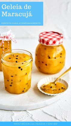 two jars filled with jam sitting on top of a white plate next to a spoon