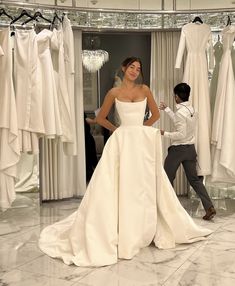 a woman standing in front of a white dress