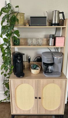 a wooden shelf with various items on it next to a potted plant and coffee maker