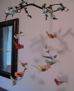 a group of birds hanging from a tree branch next to a window in a room