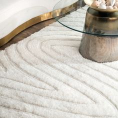 a glass table with rocks on it in front of a white couch and rugs