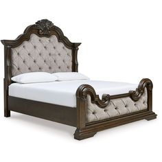 a bed that is made up and has white sheets on top of it, with an ornate headboard