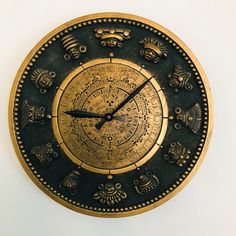 a gold and black clock with zodiac signs on it's face is shown against a white background