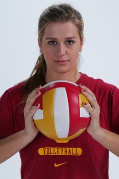 a woman holding a volleyball ball in front of her face