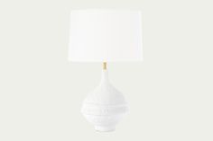 a white table lamp with a white shade on it